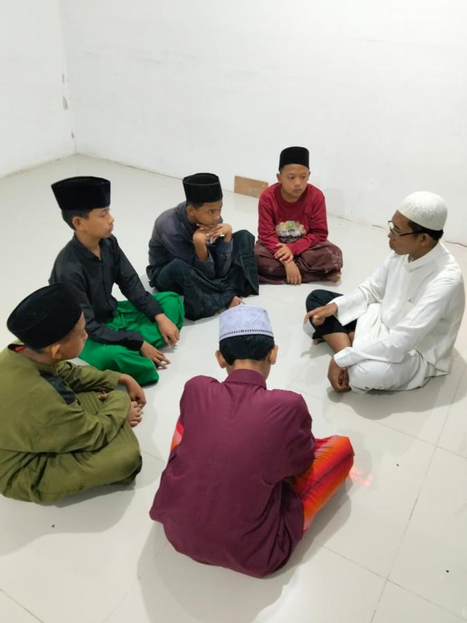 Ustadz membimbing santri yang duduk melingkar di lantai